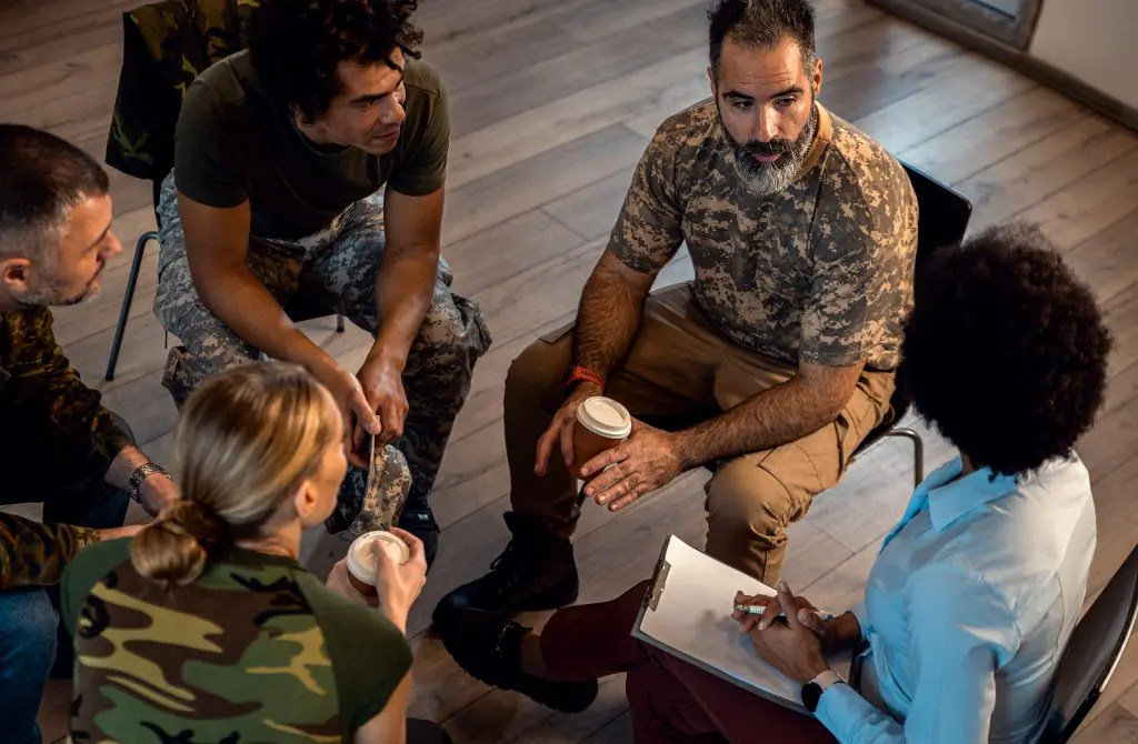 Four military soldiers are participating in a facilitated support group.