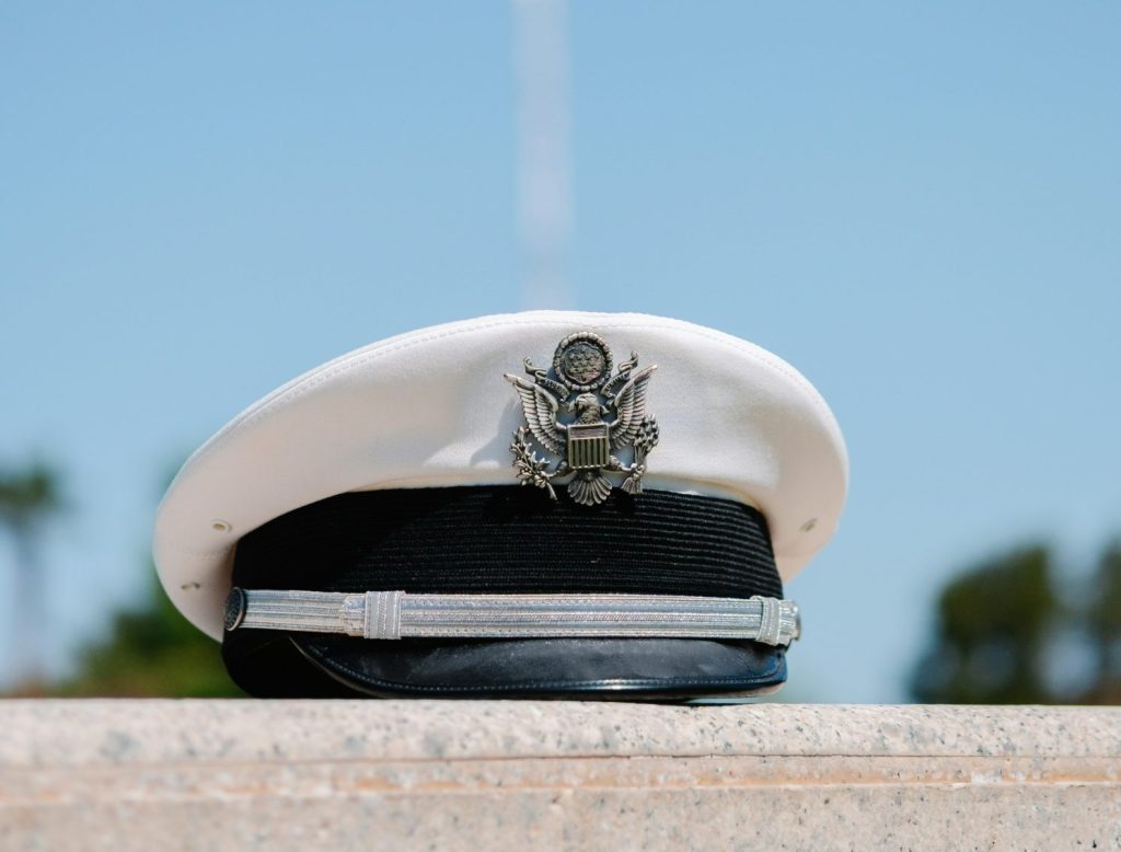 A military personnel's hat with the US flag behind it