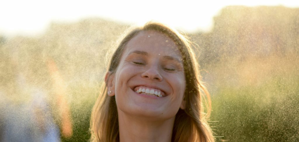 A woman with blonde, shoulder-length hair smiling with her eyes closed