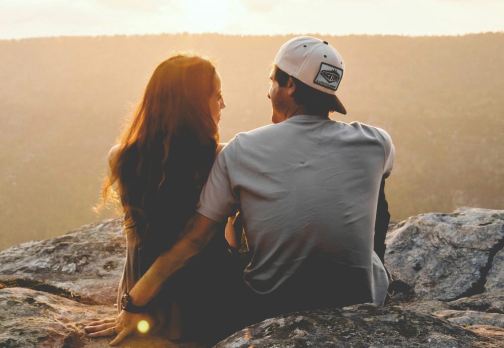A couple at the top of the mountain, looking at each other