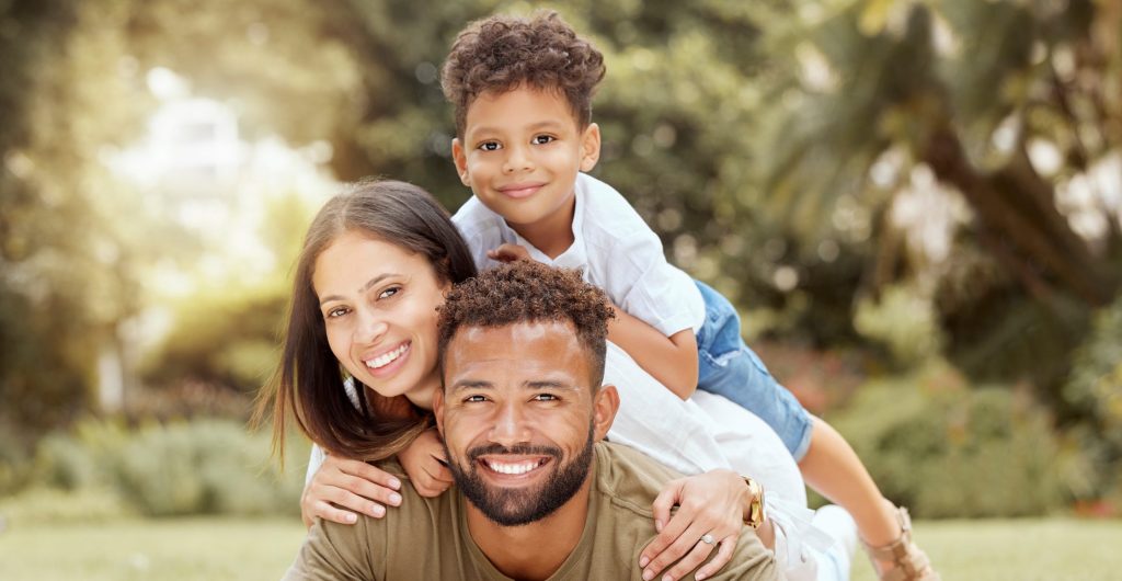happy father, mother, and son laying on top of each other on picnic blanket